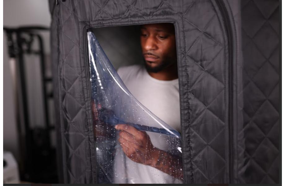 Man inside a SaunaBox sauna zipping it up to keep the heat in