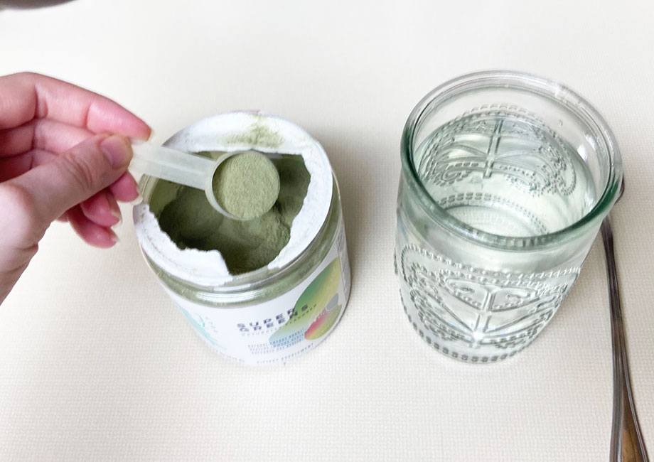 scoop of super greens into a clear glass. The powder is very fine and a light green